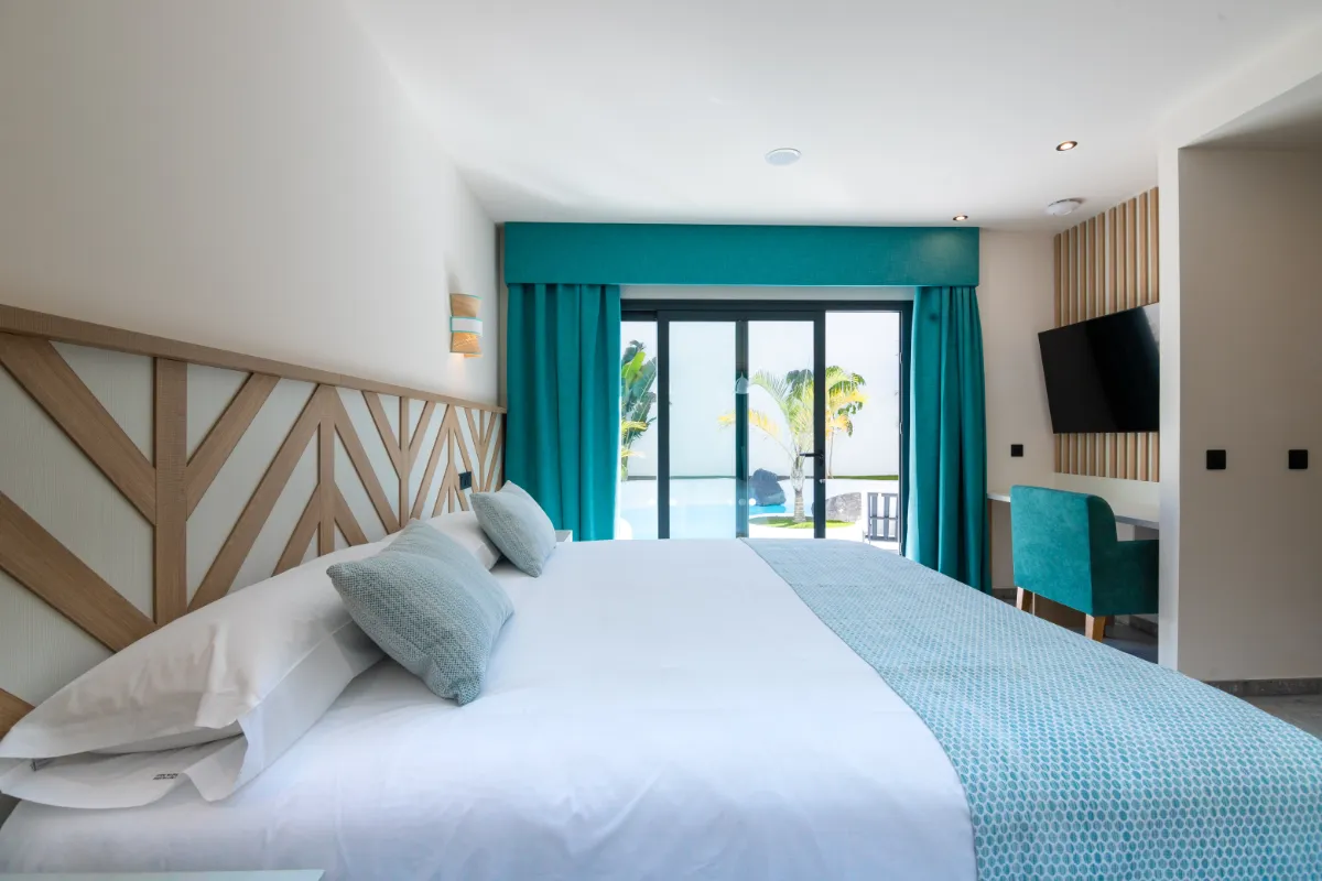 Habitación moderna con cama, cortinas azules y ventana al jardín.