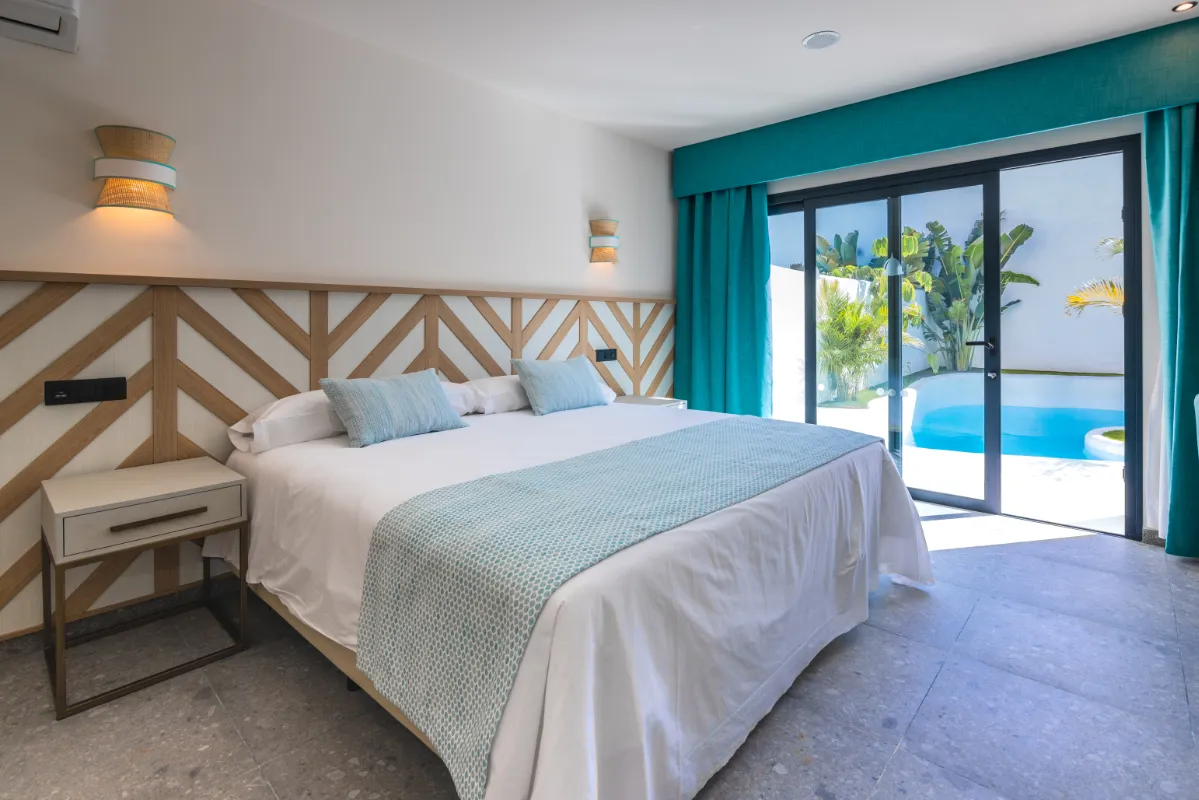 Habitación elegante con cama grande y vista a una piscina privada.