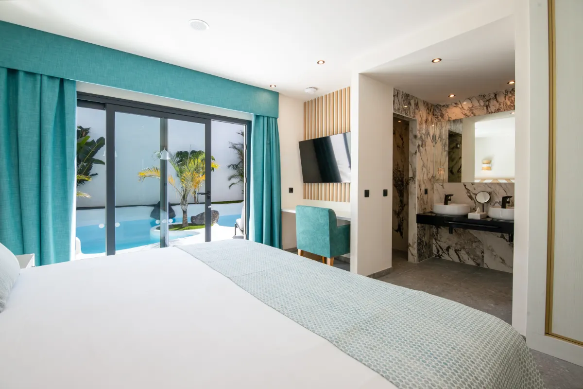 Habitación moderna con cama, escritorio, baño y vista a la piscina.