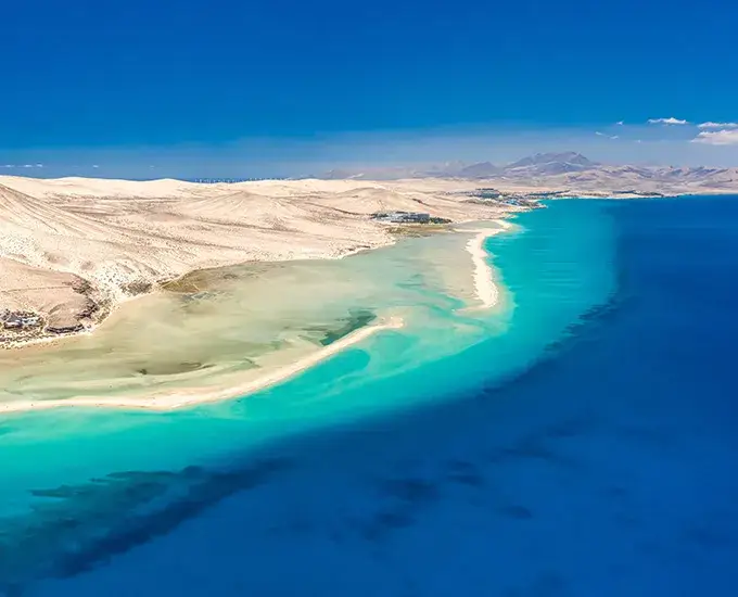 Vista a&eacute;rea de una playa con aguas turquesas y arena dorada.
