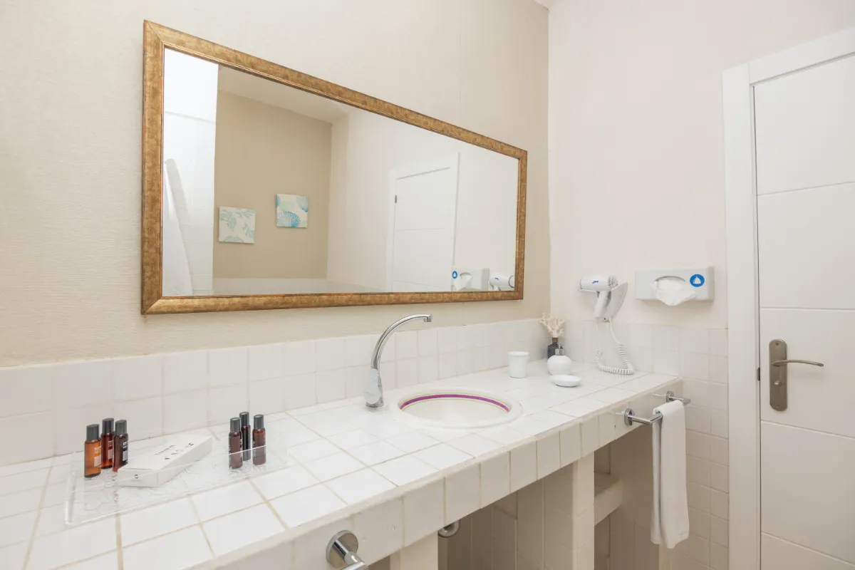 Baño con espejo grande, grifo moderno y artículos de tocador.