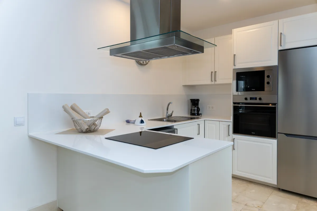 Cocina moderna con electrodomésticos de acero inoxidable y encimeras blancas.