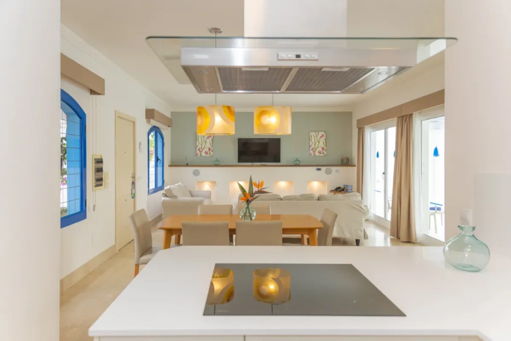 Cocina moderna con sala y comedor de dise&ntilde;o elegante y l&aacute;mparas colgantes.