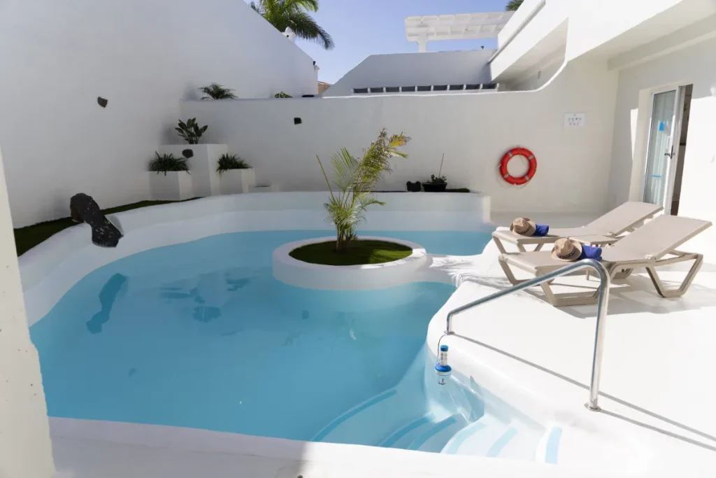 Piscina moderna con tumbonas y plantas en un entorno minimalista.