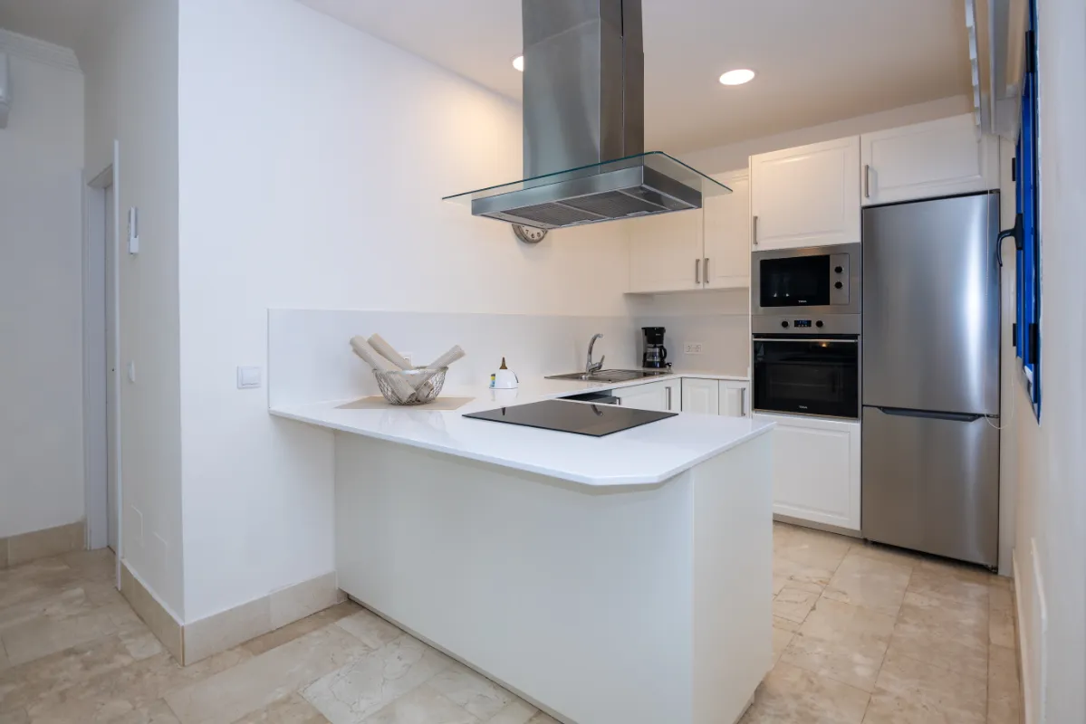 Cocina moderna con isla, campana, electrodomésticos acero inoxidable.