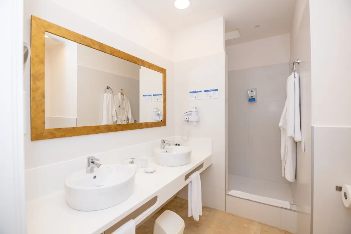 Baño moderno con dos lavabos, espejo grande y ducha.