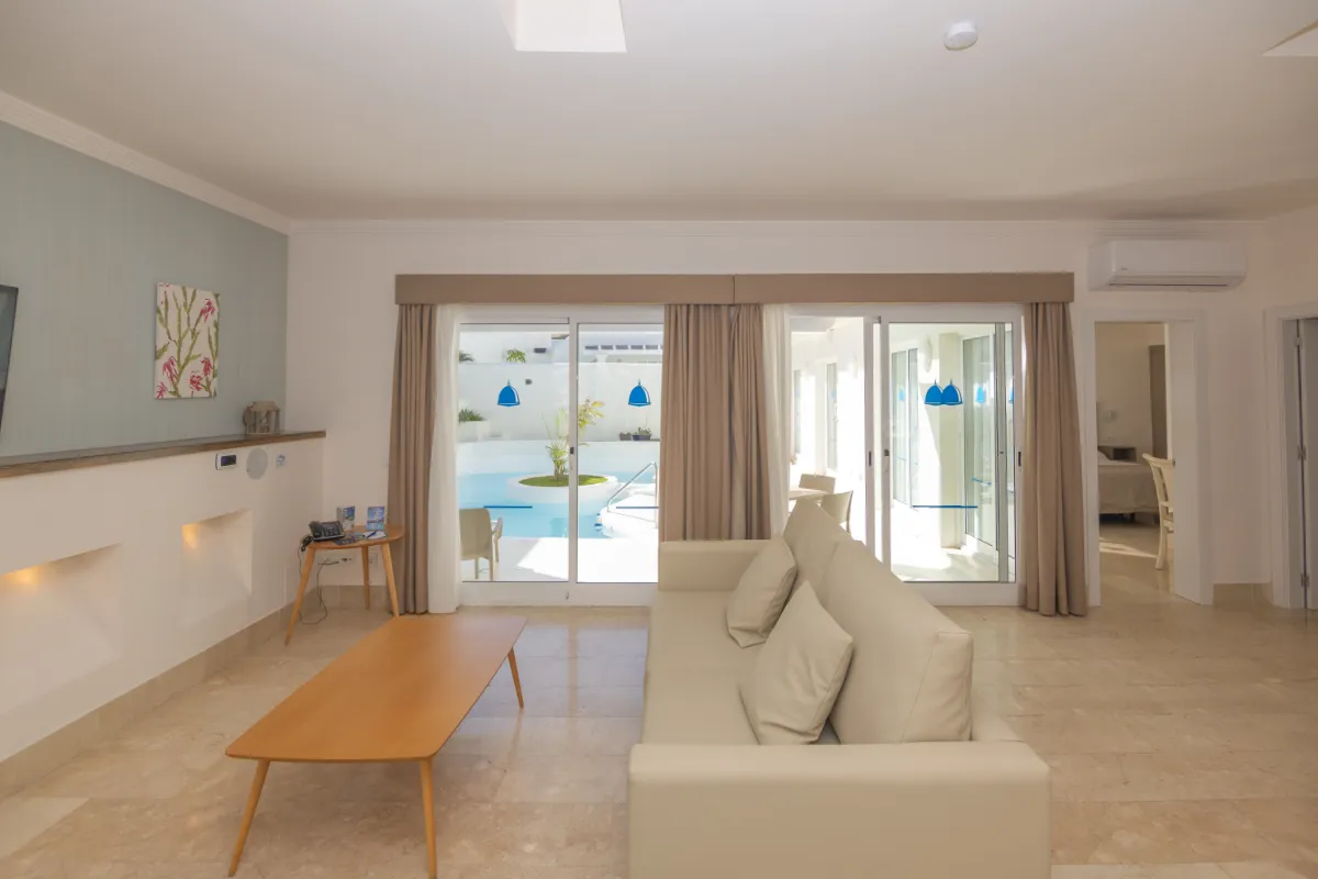 Sala moderna con sofá, mesa de centro y vista a la piscina exterior.