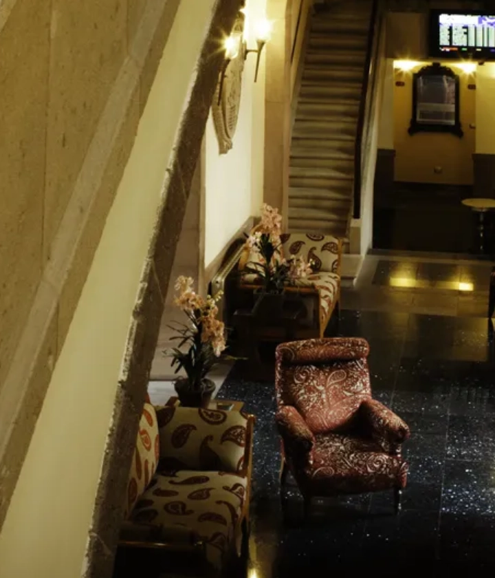 Vest&iacute;bulo elegante con sillones decorados y escaleras al fondo.