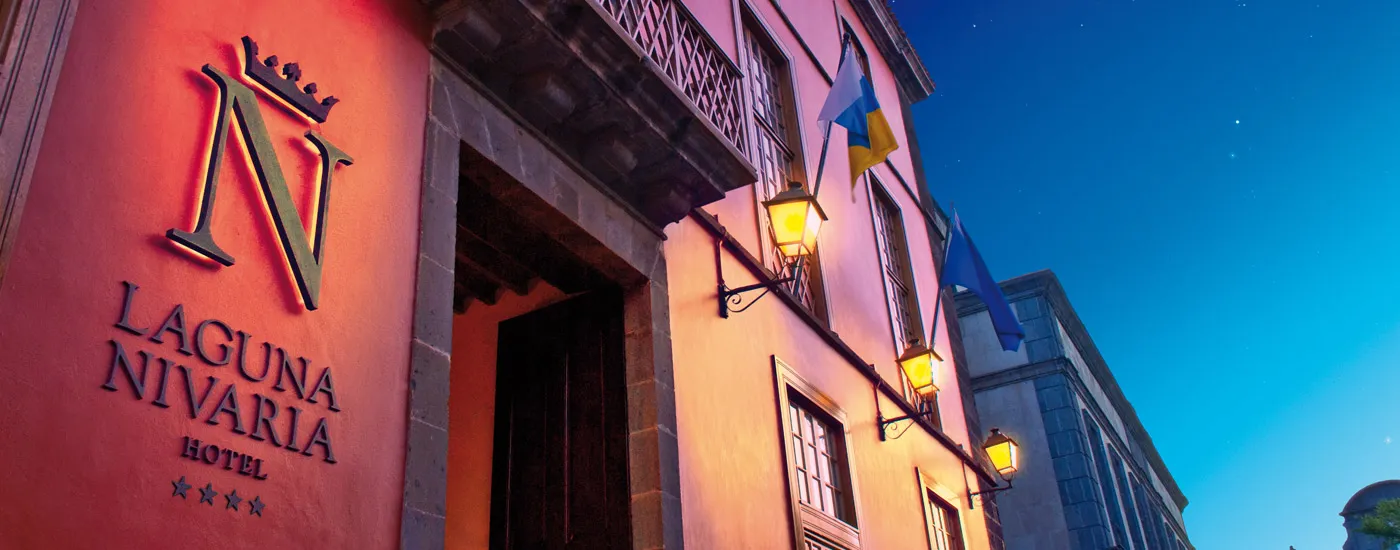 Entrada iluminada del Hotel Laguna Nivaria al anochecer con banderas.