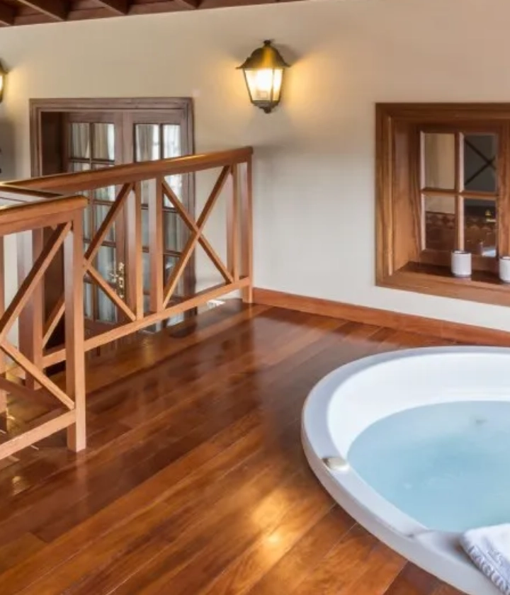 Piso de madera con jacuzzi junto a ventana y baranda de madera.