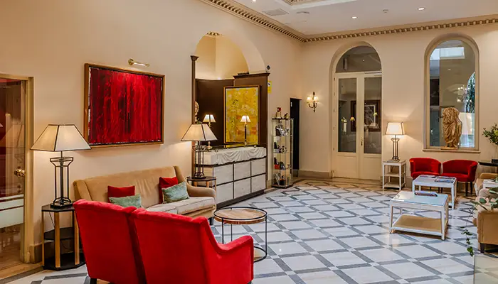 Sala elegante con sillones rojos, l&aacute;mparas y cuadros en un ambiente acogedor.