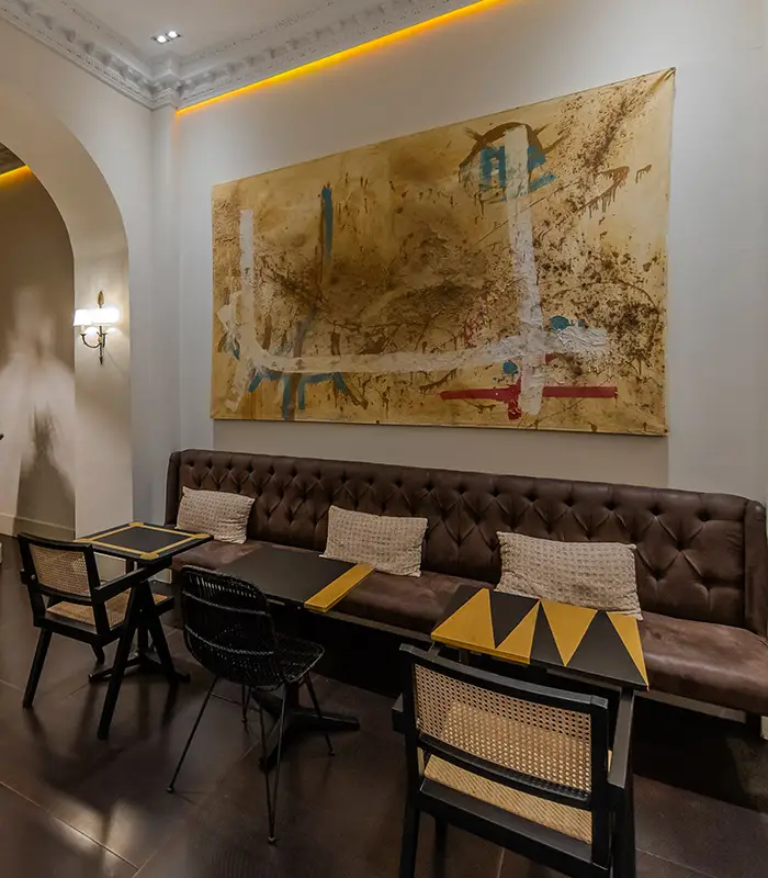 Espacio acogedor con mesas, sillas y arte abstracto en la pared.