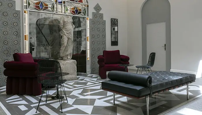 Sala con muebles modernos y una escultura cl&aacute;sica sobre un suelo geom&eacute;trico.