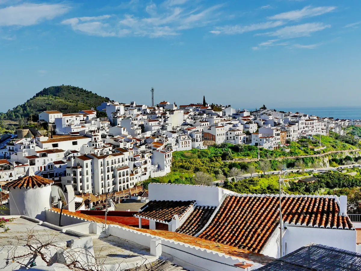 Pueblo blanco en una colina con horizonte mar&iacute;timo y cielo azul claro.