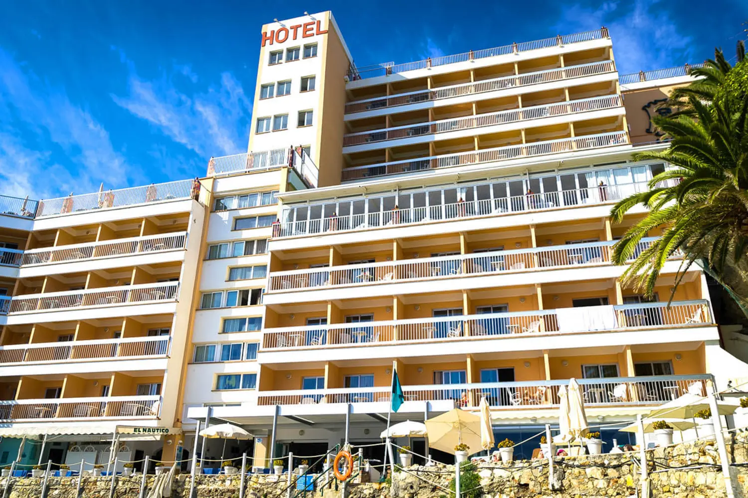 Edificio de hotel con varias terrazas bajo un cielo azul.