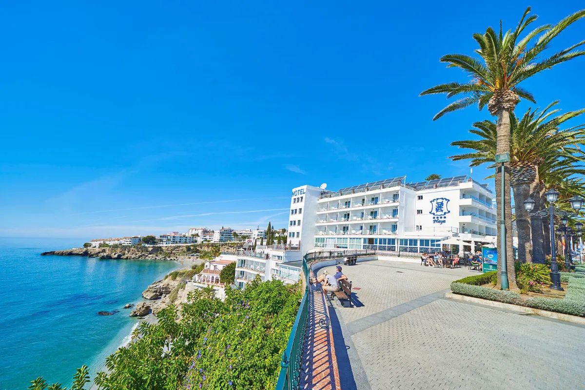 Vista de un paseo mar&iacute;timo con hotel junto al mar y cielo despejado.