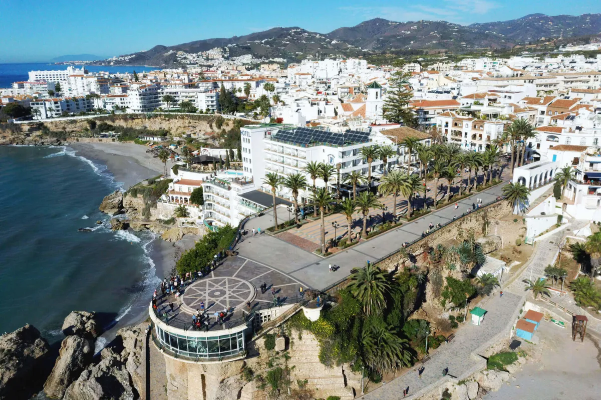 Vista a&eacute;rea de una ciudad costera con plaza y mar al fondo.