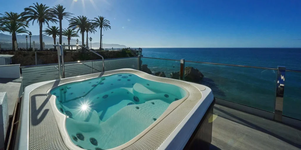 Jacuzzi con vista al mar y palmeras bajo un cielo azul y soleado.