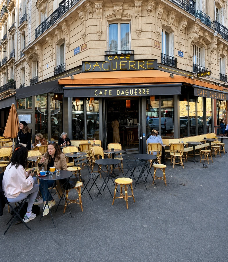 Terrasse du caf&eacute; Daguerre &agrave; Paris, tables et chaises devant un immeuble haussmannien