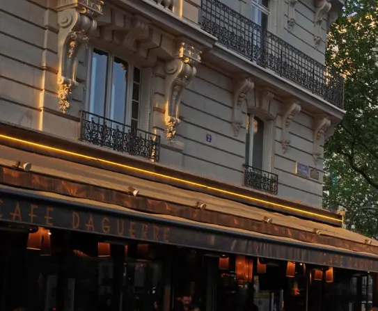 Fa&ccedil;ade d&rsquo;un caf&eacute; parisien avec guirlande lumineuse et balcons en pierre.