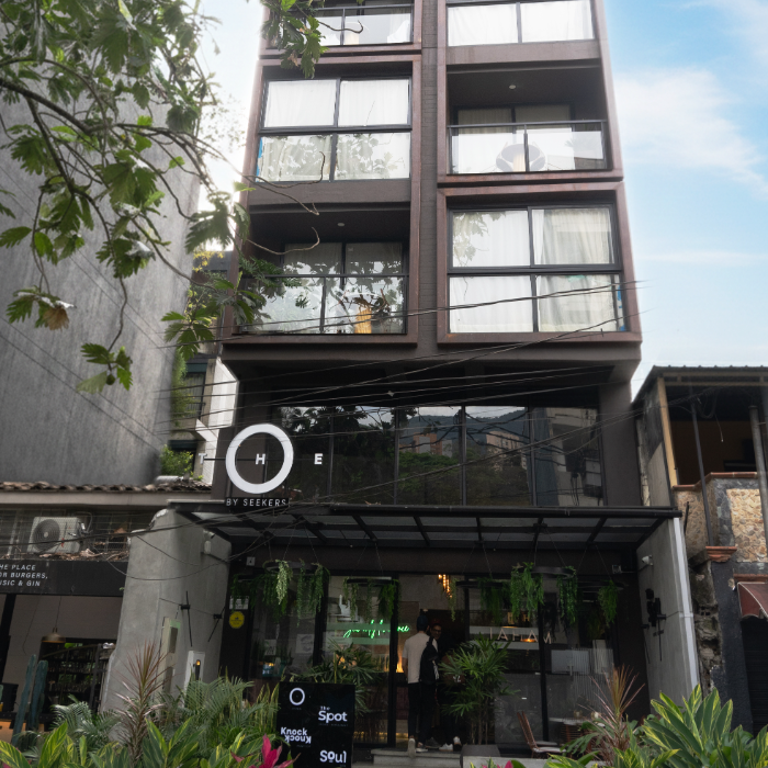 Edificio moderno de varios pisos con ventanas, plantas y letrero "THE".