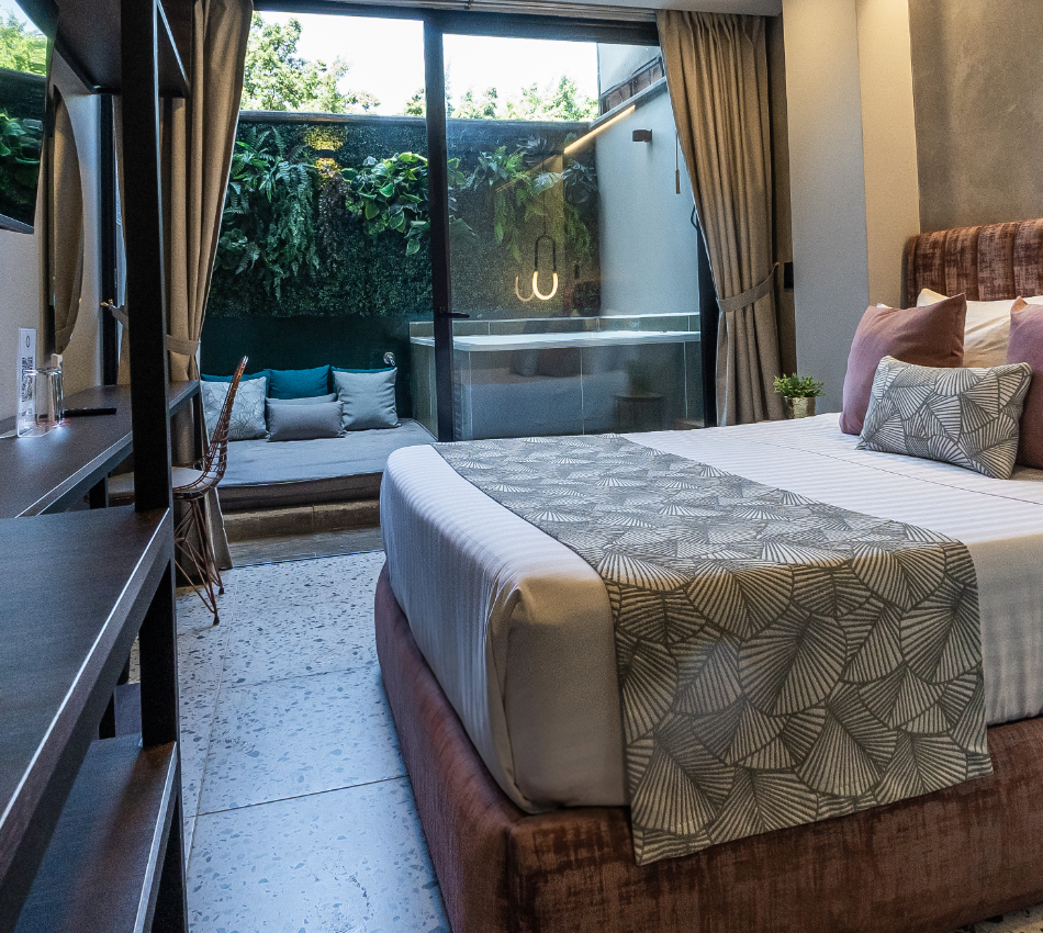 Habitaci&oacute;n moderna con cama amplia, ventana y peque&ntilde;a terraza con jacuzzi.