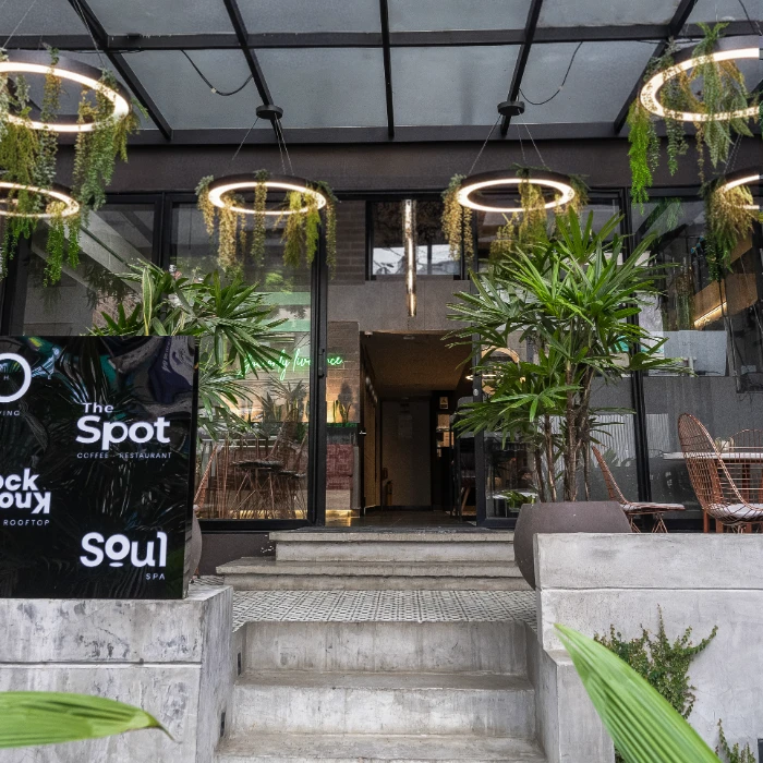 Entrada de un caf&eacute; moderno con plantas y luces colgantes en la entrada.