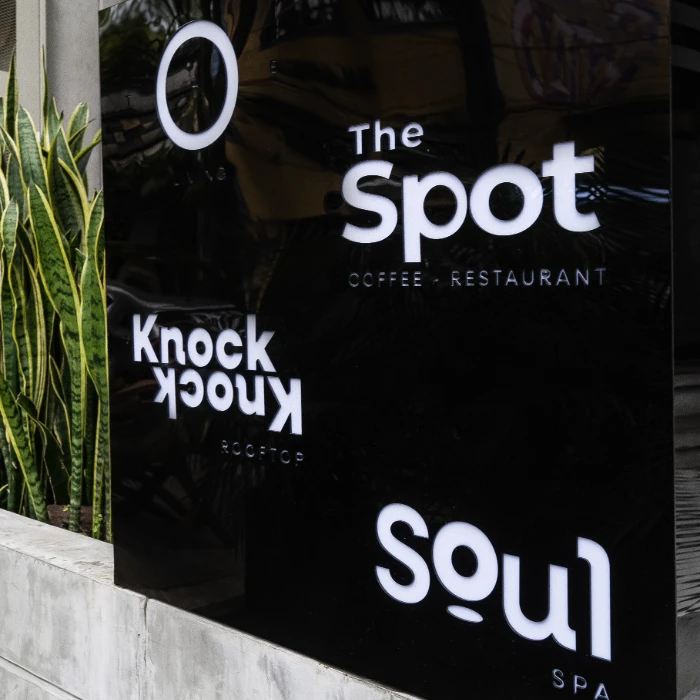 Letrero negro con textos "The Spot", "Knock Knock" y "Soul", y plantas al lado.