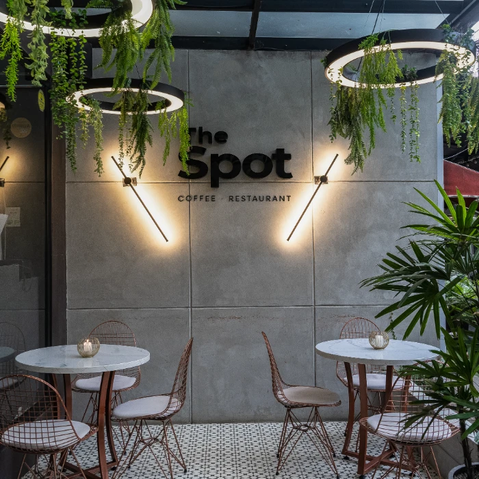 Cafeter&iacute;a moderna con mesas, luces y plantas colgantes.