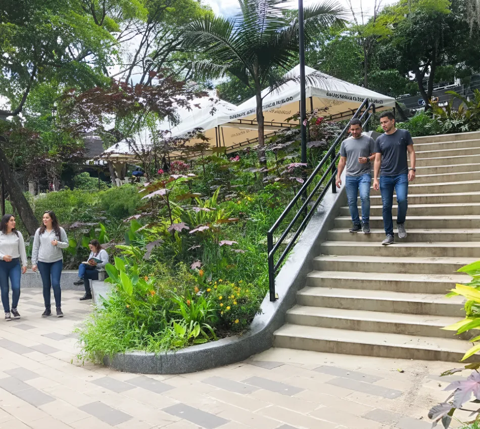Gente caminando en un parque con escaleras y vegetaci&oacute;n alrededor.