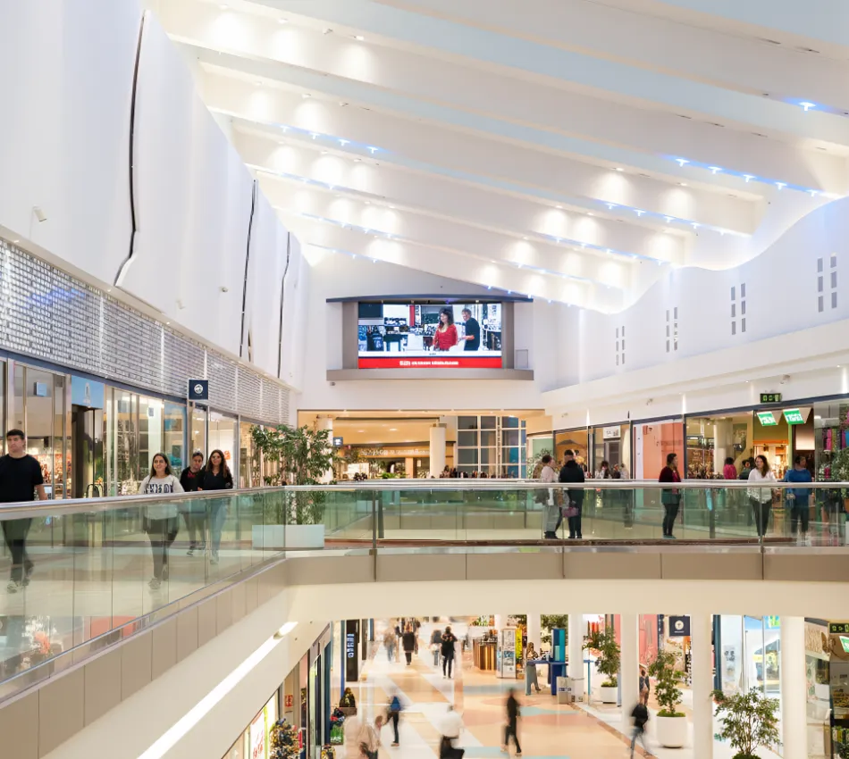 Centro comercial con gente paseando por sus pasillos iluminados.