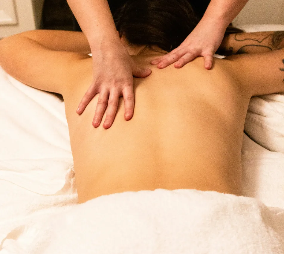 Persona recibiendo un masaje en la espalda sobre una toalla blanca.