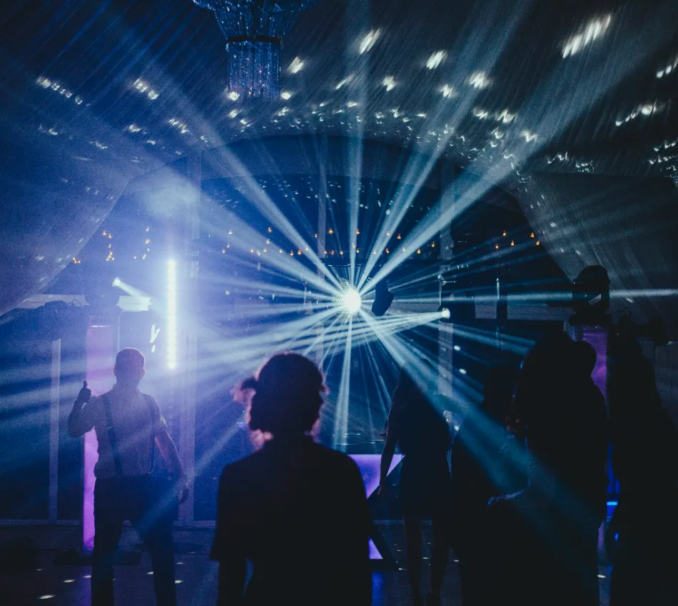 Personas bailando con luces de discoteca y una bola de espejos brillante.