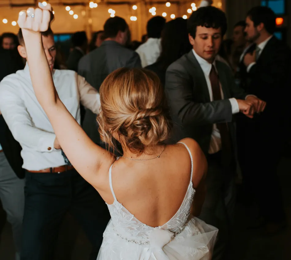 Grupo de personas bailando en una fiesta con luces colgantes.