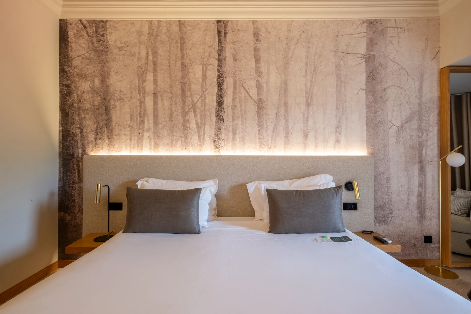 Quarto de hotel com cama grande e papel de parede de floresta.