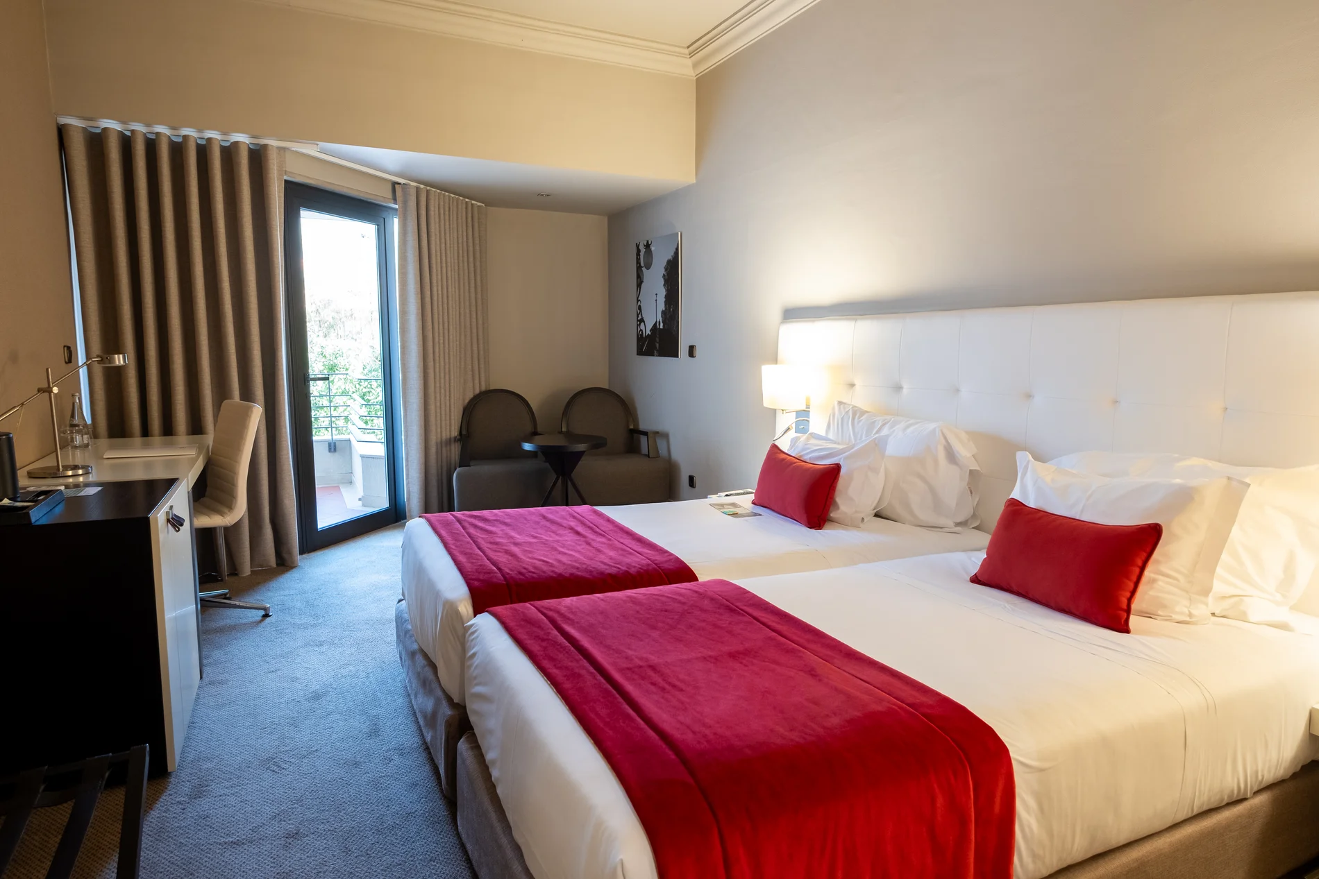 Quarto de hotel moderno com duas camas e detalhes em vermelho.