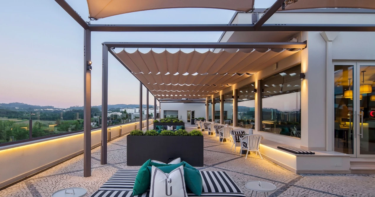Terra&ccedil;o moderno com poltronas e mesas ao ar livre ao entardecer.