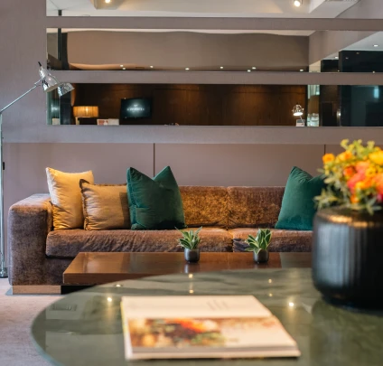 Sala de estar aconchegante com sof&aacute;, almofadas verdes e mesa decorada.