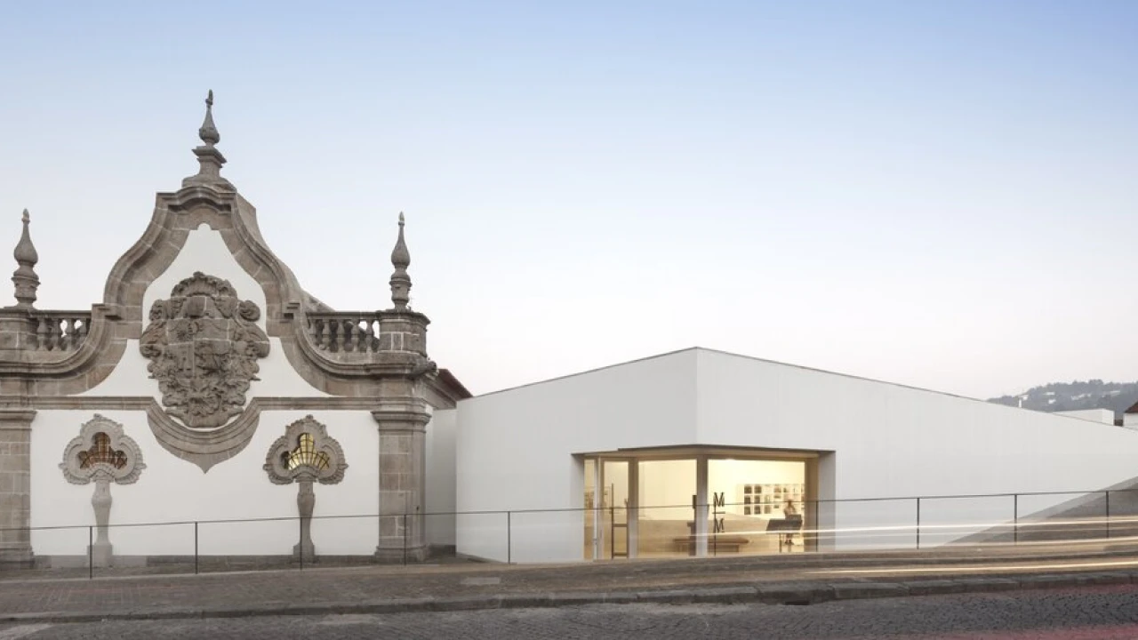 Edif&iacute;cio com fachada cl&aacute;ssica e estrutura moderna ao fundo.