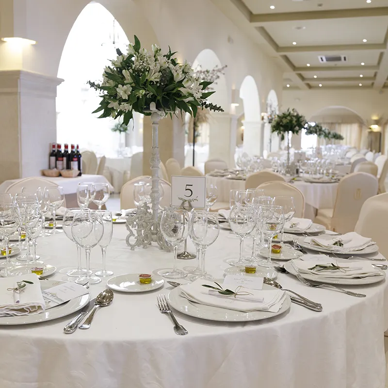 Mesa de banquete con vajilla blanca y flores blancas en un sal&oacute;n elegante