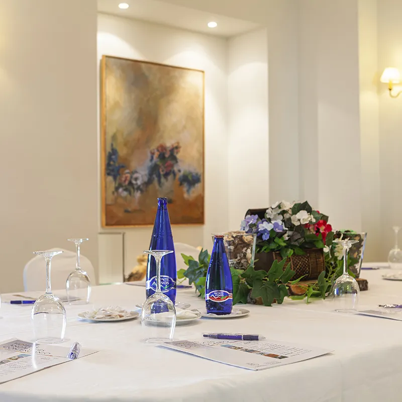 Mesa con botellas azules y flores en un sal&oacute;n con cuadros al fondo