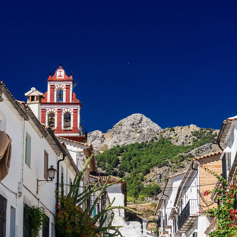 Iglesia con campanario en un pueblo blanco y monta&ntilde;as al fondo