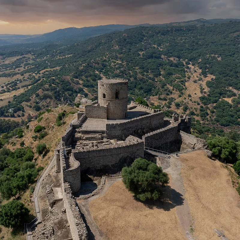 Fortaleza de piedra en una colina con paisaje monta&ntilde;oso y valle al atardecer