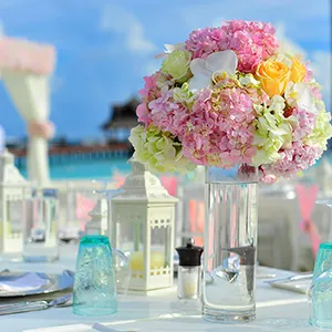 Ramo de flores rosas y blancas en mesa decorada con jarrones y velas