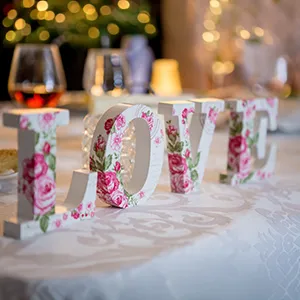 Mesa con n&uacute;meros &ldquo;2024&rdquo; decorados con flores y fondo de luces navide&ntilde;as.