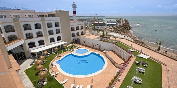 Vista de hotel con piscina y playa frente al mar desde un mirador.