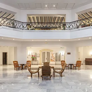 Sal&oacute;n amplio y luminoso con sillas, mesa y vista de ventanales decorativos.