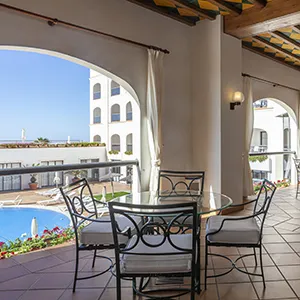 Terraza con mesas y sillas de hierro y arcos sobre el mar, vista azul