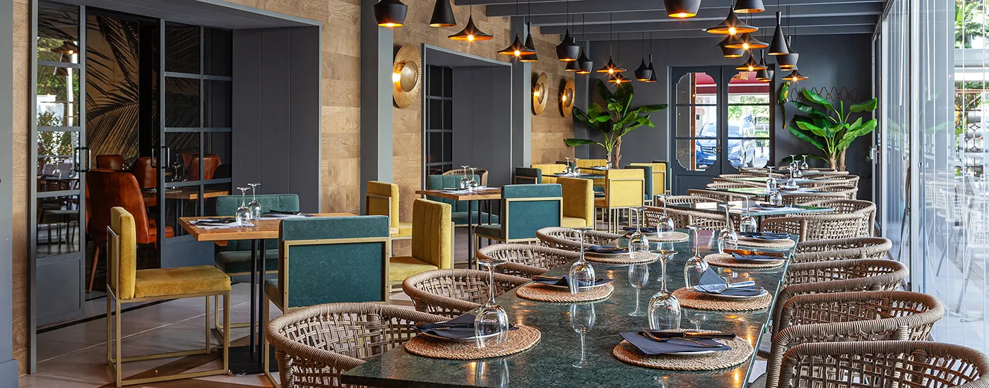 Restaurante moderno con mesas, sillas de rat&aacute;n y luces colgantes en interior elegante