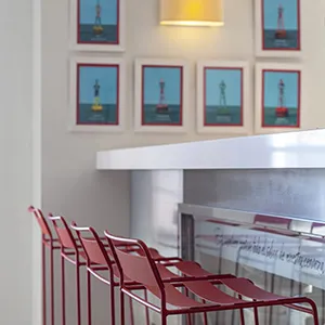 Sillas rojas en sala con cuadros y chimenea blanca decorativa.